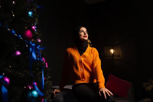 Muslim woman in black hijab near new year tree waiting for celebration of Christmas. Islam religion