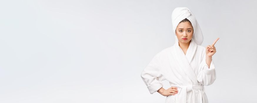 Beauty portrait of young woman showing and pointing finger to empty copy space, asian beauty in bathrobe