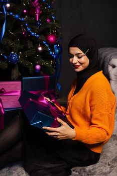 Muslim woman with gift near new year tree. Christmas celebration of islam religion people