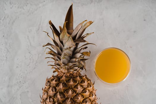 Pineapple fruit and juice in double glass cup on white stone background. Tropical fruit Pouring yellow tropical juice into glass.