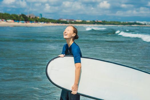 Young woman in swimsuit with surf for beginners ready to surf. Positive emotions.