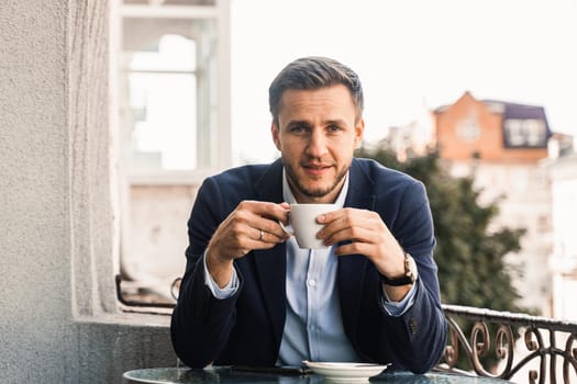 Man like coffee. Handsome man with cup of coffee in cafe. Morning lifestyle of male. Man is sitting on the summer terrace in cafe, drinking coffee and smiling