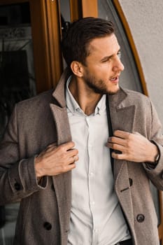 Handsome bearded business man in coat posing outside. Male lifestyle