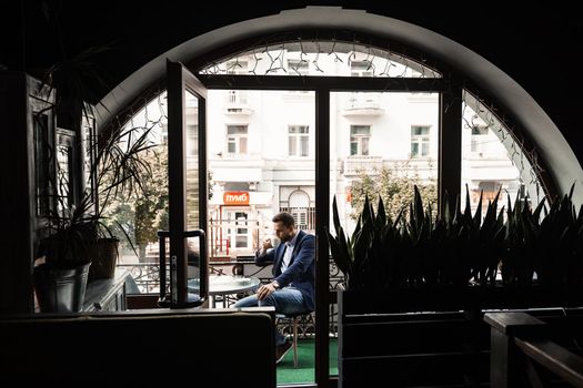 Man like coffee. Handsome man with cup of coffee in cafe. Morning lifestyle of male. Man is sitting on the summer terrace in cafe, drinking coffee and smiling