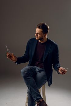 Handsome surgeon with needle holder and surgical knife weared casual suit in studio. Confident business man on dark background