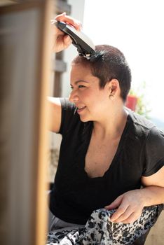 Happy young woman shaving your hair head with a razor machine and smiling at home, vertical high quality photo