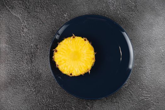 Piece of pineapple on blue plate close-up. Slice of yellow tropical fruit.