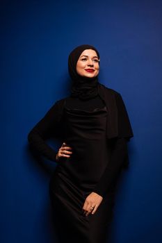 Fashion muslim model in black hijab is posing on blue background in studio. Islam religion