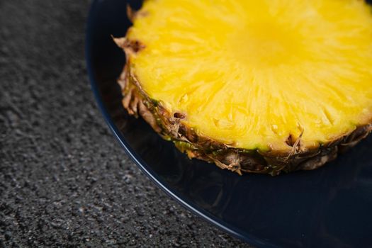 Piece of pineapple on blue plate close-up. Slice of yellow tropical fruit.