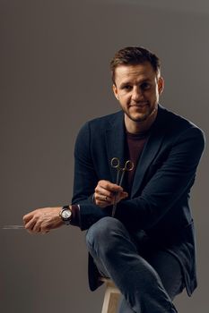 Doctor with surgical equipment needle and scissors. Handsome man weared casual business suit. Portrait of surgeon in studio