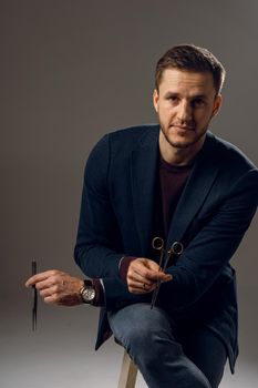 Doctor with surgical equipment needle and scissors. Handsome man weared casual business suit. Portrait of surgeon in studio