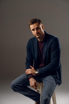 Handsome surgeon with needle holder and surgical knife weared casual suit in studio. Confident business man on dark background