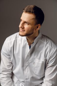 Surgeon weared in medical robe on dark background. Handsome doctor posing in studio