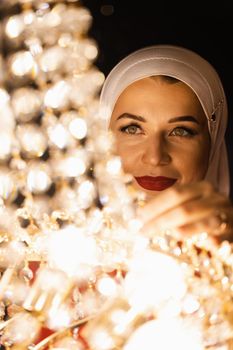 Fashion muslim model near big expensive chandelier. Islamic religion