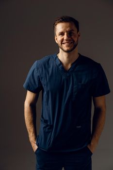 Surgeon weared in medical robe on dark background. Handsome doctor posing in studio