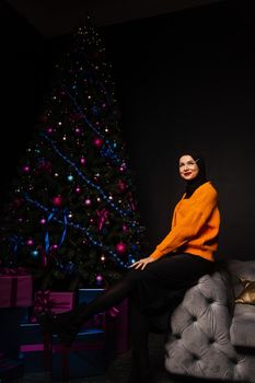 Muslim woman in black hijab near new year tree waiting for celebration of Christmas. Islam religion