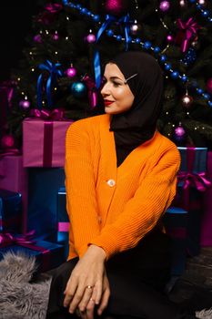 Muslim girl in black hijab is dreaming about gift at new year holiday. Christmas celebration of islamic religion people