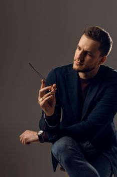 Doctor with surgical equipment needle and scissors. Handsome man weared casual business suit. Portrait of surgeon in studio