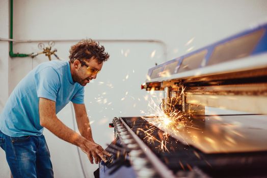 Within heavy industry. A man works in a modern factory on a CNC machine. Selective focus. High-quality photo