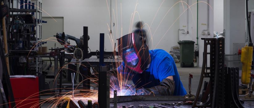 Professional Heavy Industry Welder Working Inside the factory, Wears Helmet and Starts Welding. Selective Focus. High-quality photo