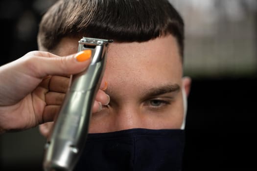 Barbershop customer in medical mask for protection against coronavirus covid-19. Making hairstyle for handsome man