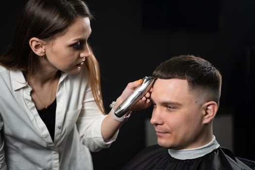 Trimming bangs of handsome man in barbershop. Woman hairdresser making hair style
