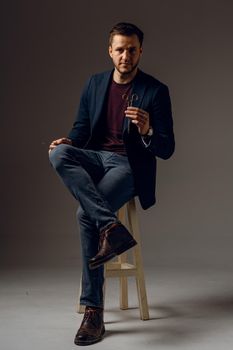 Handsome surgeon with needle holder and surgical knife weared casual suit in studio. Confident business man on dark background