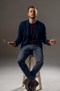 Handsome surgeon with needle holder and surgical knife weared casual suit in studio. Confident business man on dark background