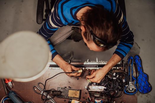 Industrial worker man soldering cables of manufacturing equipment in a factory. Selective focus. High-quality photo