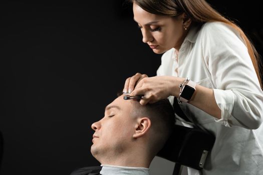 Straight razor cut man hair in barbershop. Attractive woman barber making hairstyle for handsome man