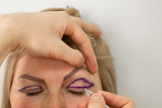 Blepharoplasty markup close-up on the face before the plastic surgery operation for modifying the eye region of the face in medical clinic. Doctor doing plastic cosmetic operation