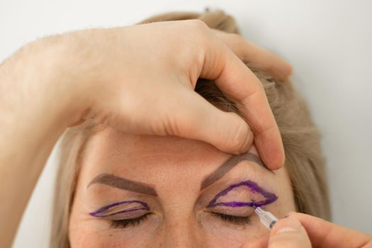 Blepharoplasty markup close-up on the face before the plastic surgery operation for modifying the eye region of the face in medical clinic. Doctor doing plastic cosmetic operation