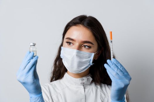 Doctor holding coronavirus vaccine. Covid-19 Vaccination. Stop quarantine. Attractive girl in medical gloves with syringe and medication