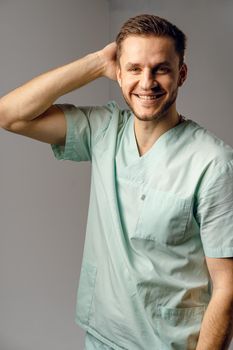 Surgeon weared in medical robe smile and posing on white background. Handsome happy doctor posing in studio