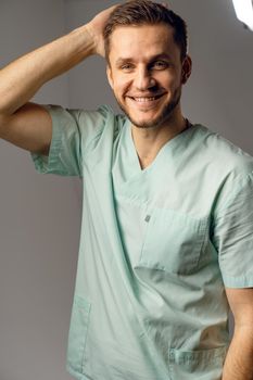 Surgeon weared in medical robe smile and posing on white background. Handsome happy doctor posing in studio