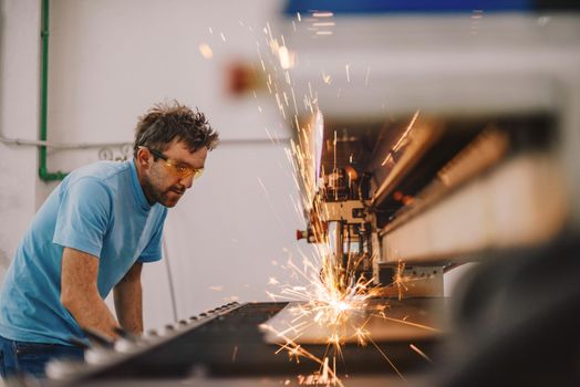 Within heavy industry. A man works in a modern factory on a CNC machine. Selective focus. High-quality photo