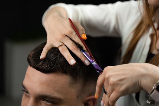 Haircut and styling in barbershop for handsome man. Woman making hairstyle using scissors