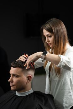 Haircut and styling in barbershop for handsome man. Woman making hairstyle using scissors