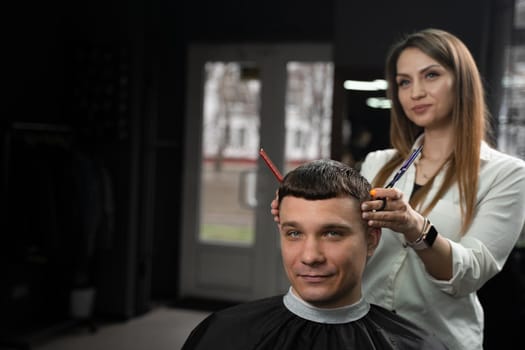 Haircut and styling in barbershop for handsome man. Woman making hairstyle using scissors