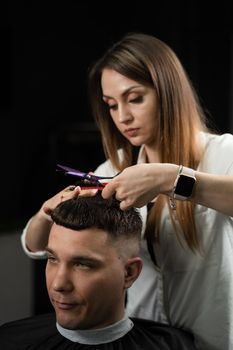 Haircut and styling in barbershop for handsome man. Woman making hairstyle using scissors