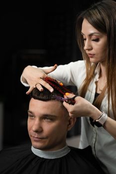 Haircut and styling in barbershop for handsome man. Woman making hairstyle using scissors