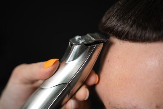 Trimming bangs of handsome man in barbershop. Woman hairdresser making hair style