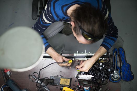 Industrial worker man soldering cables of manufacturing equipment in a factory. Selective focus. High quality photo