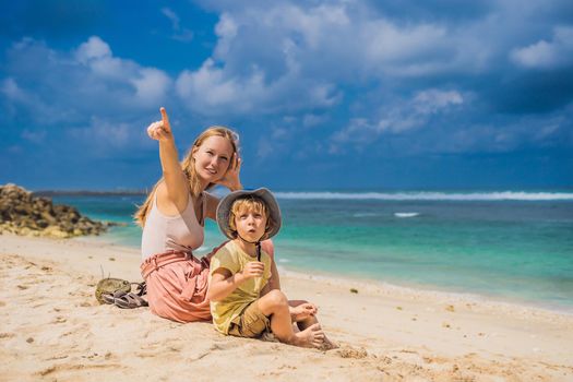 Mom and son travelers on amazing Melasti Beach with turquoise water, Bali Island Indonesia. Traveling with kids concept.