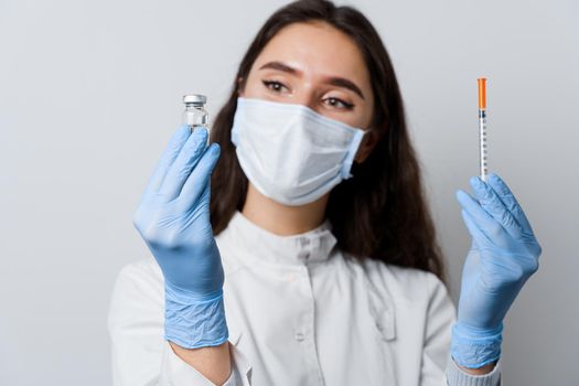 Doctor holding coronavirus vaccine. Covid-19 Vaccination. Stop quarantine. Attractive girl in medical gloves with syringe and medication