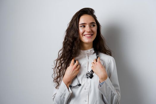 Young attractive girl doctor in medical robe. Young woman smiling on white background. Advert for medical clinic and blogs.