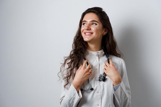 Young attractive girl doctor in medical robe. Young woman smiling on white background. Advert for medical clinic and blogs.