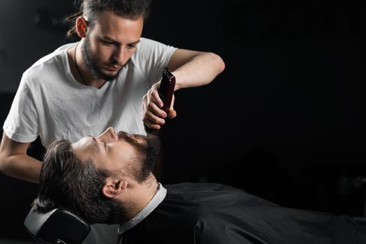 Trimming the beard with a shaving machine. Advertising for barbershop and men's beauty salon.