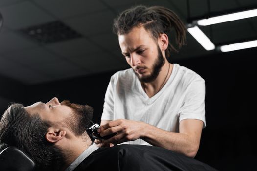 Trimming the beard with a shaving machine. Advertising for barbershop and men's beauty salon.