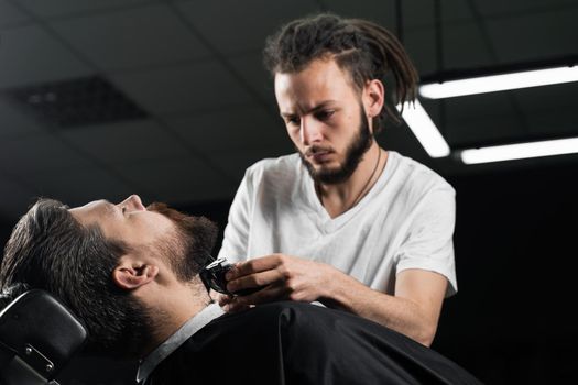 Trimming the beard with a shaving machine. Advertising for barbershop and men's beauty salon.